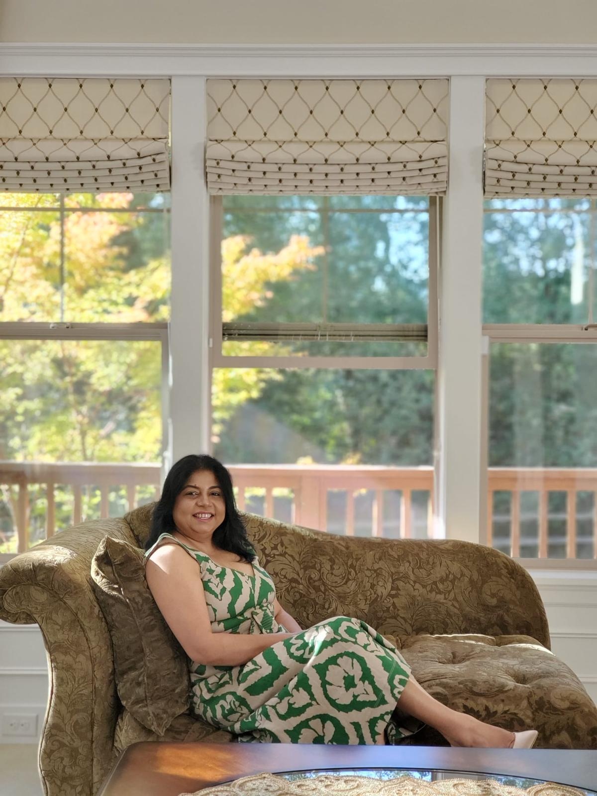 Sanchita seated on a chaise by large windows
